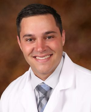 Clearwater Dental | Dr. Lance R. Rhoten smiling in a white coat with a light shirt and pale blue tie